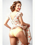 Woman wearing a floral dress with a backless design and yellow underwear on a white background